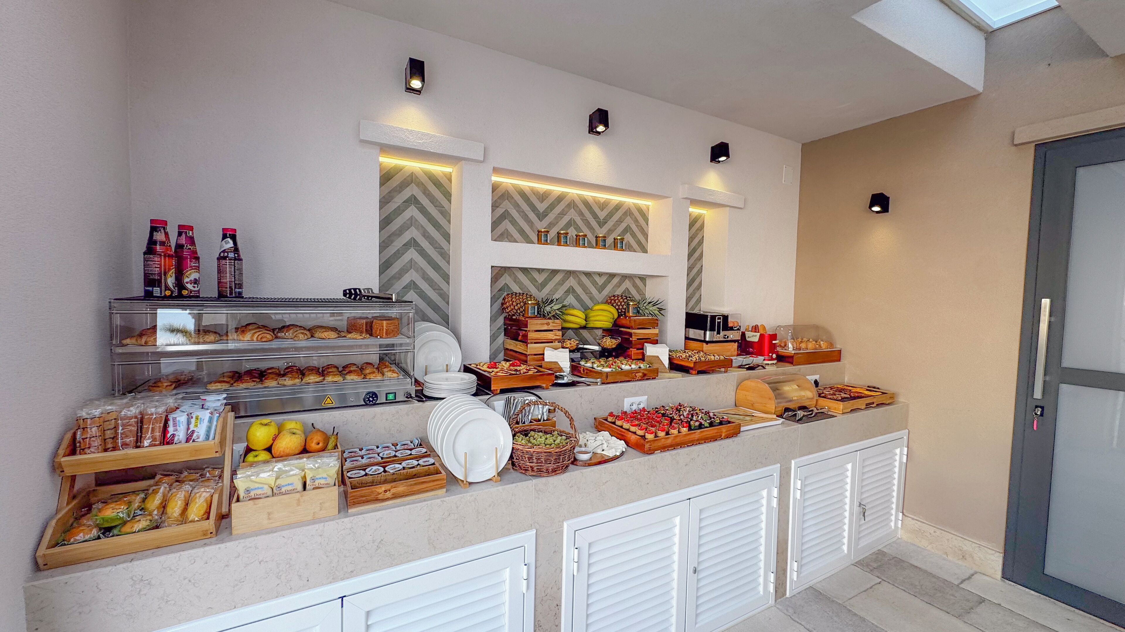 Un bufé con diversos alimentos y bebidas, incluyendo pasteles, frutas y salsas.