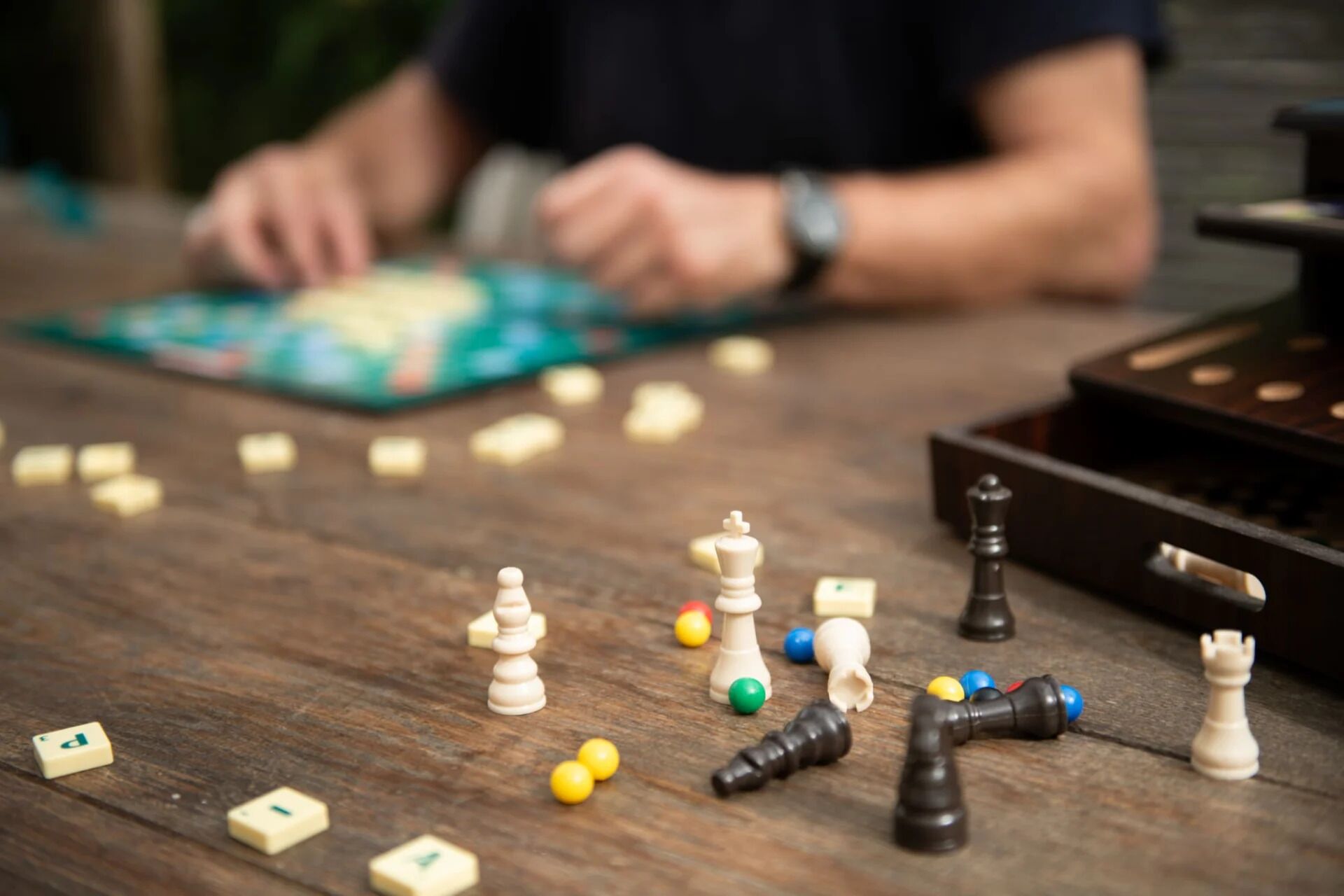 Una mesa de madera con piezas de ajedrez y de juego dispersas.