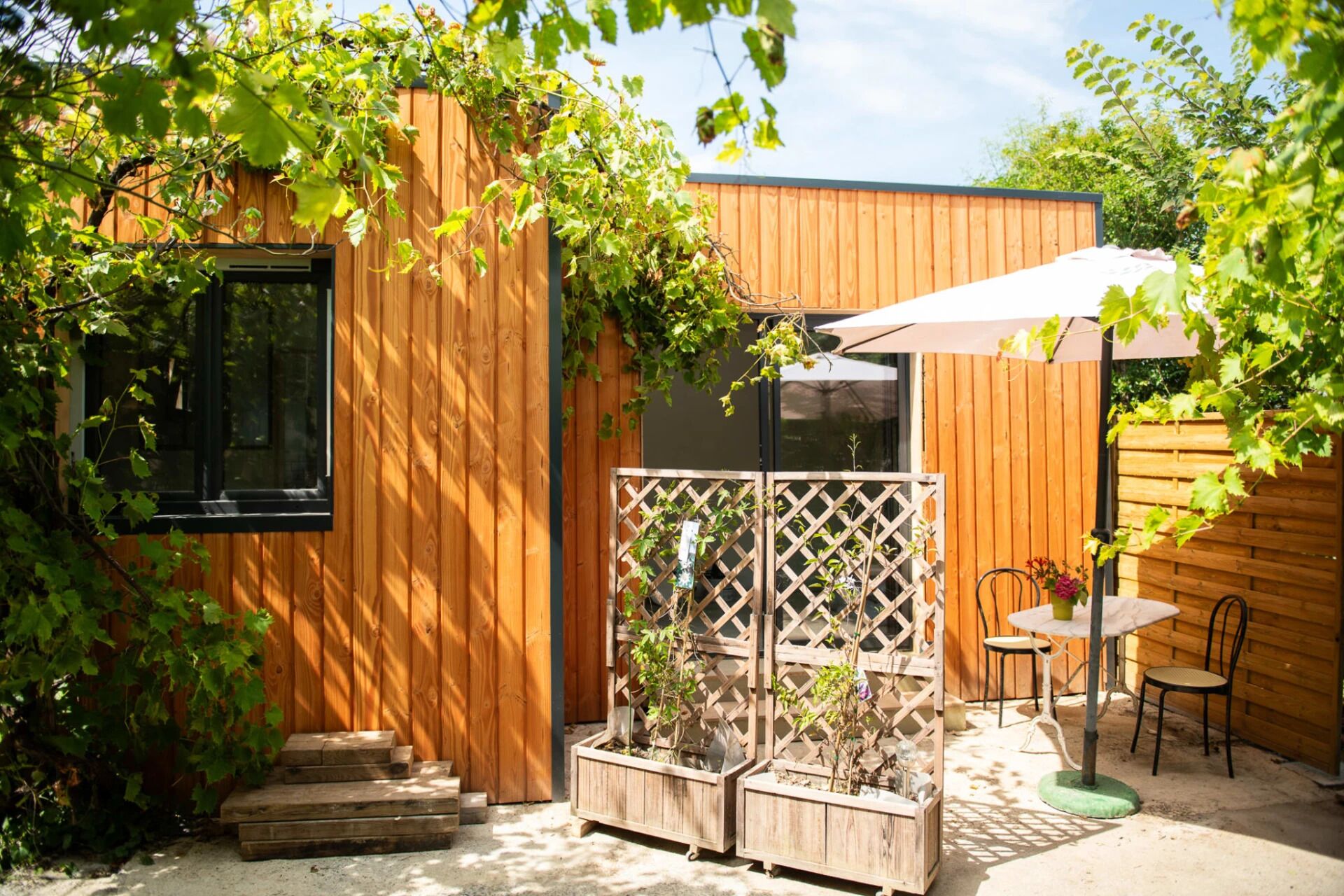 A wooden building with a window, a wooden fence, and a table with chairs.