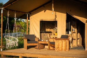 A wooden deck with a tent structure, outdoor seating, and a small table with a vase of flowers. - La Jolie Longère Fleurie (Le Gué-d'Alleré)