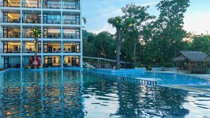 A multi-story hotel with balconies, a swimming pool, and tropical landscaping. - Fullman Hotel (Luang Prabang)