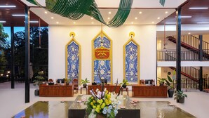 A reception area with a water feature, wooden furniture, and decorative elements. - Fullman Hotel (Luang Prabang)
