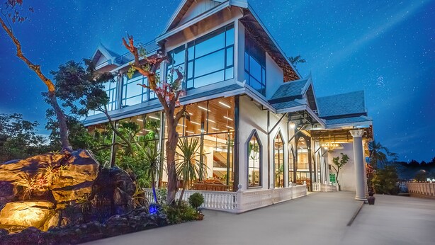 A modern house with large windows, a balcony, and a well-lit entrance. - Fullman Hotel (Luang Prabang)