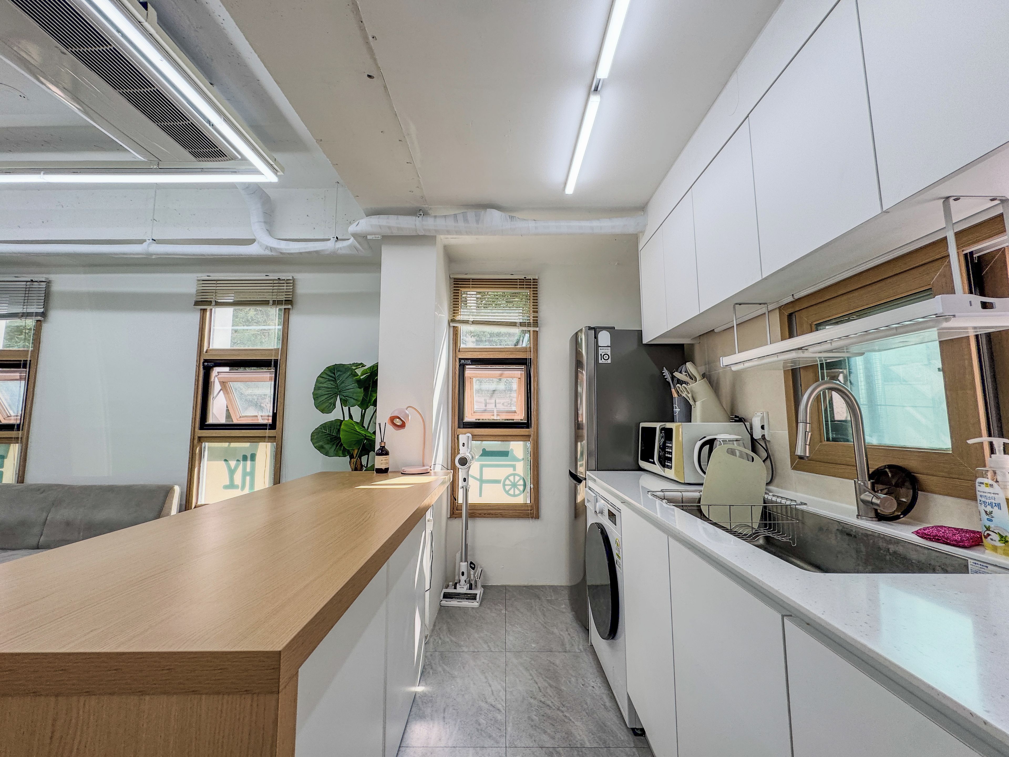 A modern kitchen with a wooden countertop, built-in appliances, and a window with blinds.