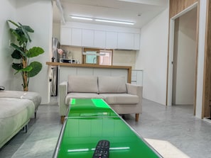 A modern living room with a sofa, a green coffee table, and a potted plant.