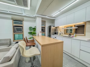 A modern kitchen with white cabinets, a wooden island, and a bar stool.