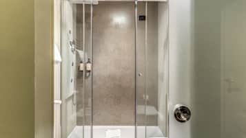 A modern bathroom with a glass-enclosed shower, a toilet, and a sink.