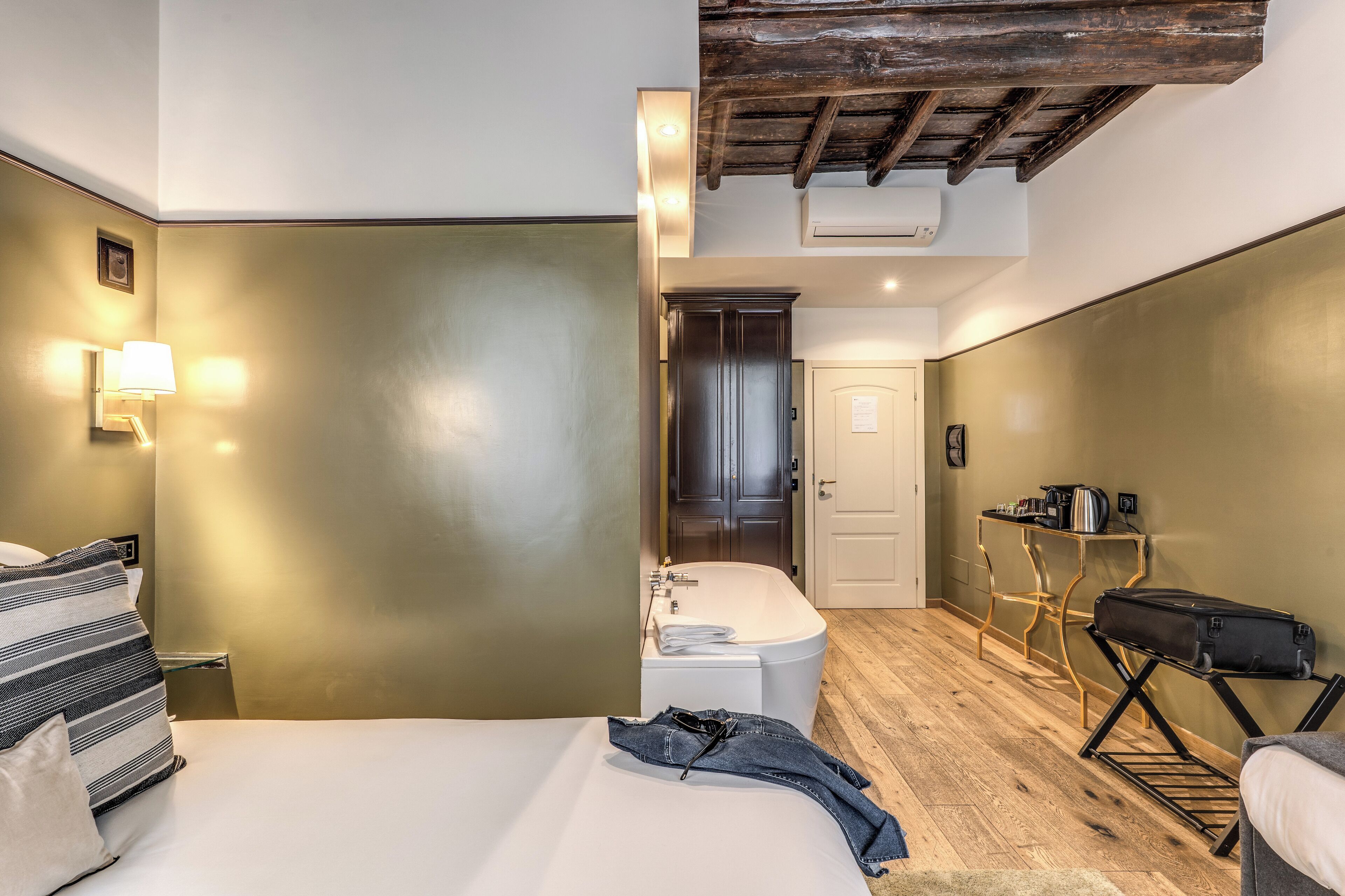 A hotel room with a bed, a bathroom with a bathtub, and a kitchenette area.
