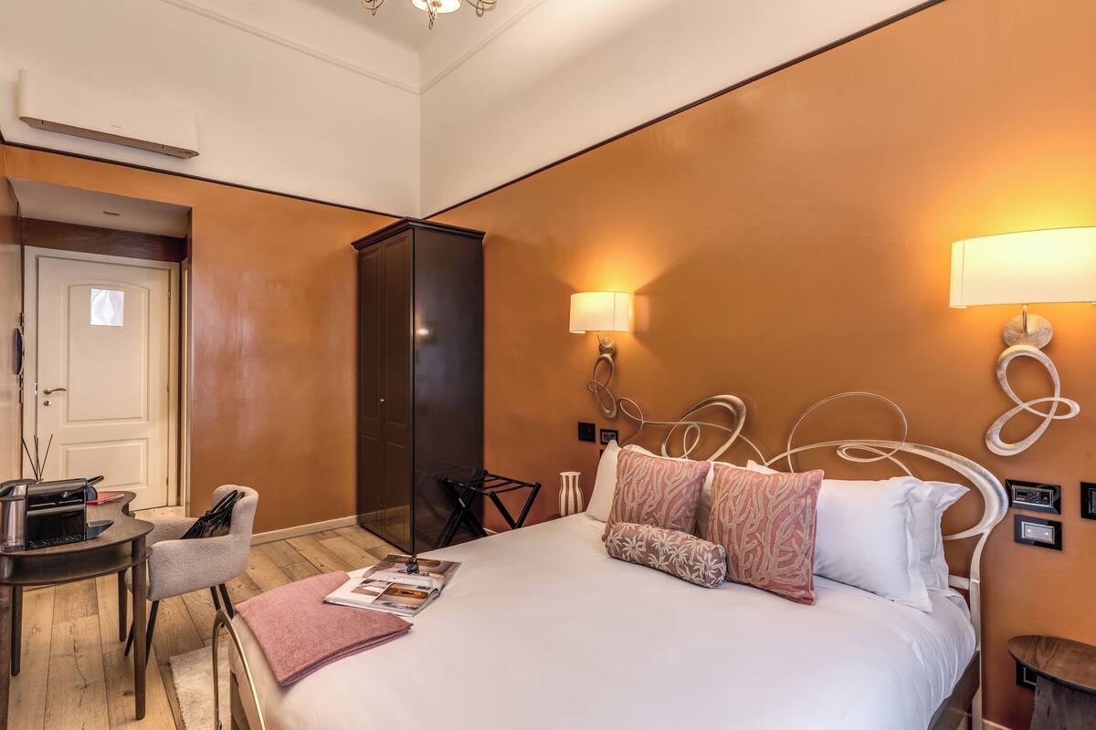 A hotel room with a bed, bedside table, chair, lamp, and a wardrobe.