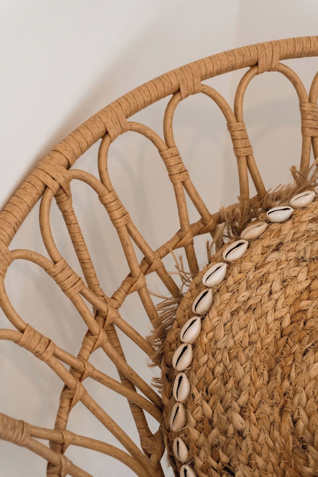 Un panier tressé, de forme circulaire, orné de coquillages décoratifs.