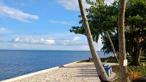 A beach with a surfboard, palm trees, and a clear view of the ocean. - Sublime Tahiti Beach Retreat (Teva I Uta)