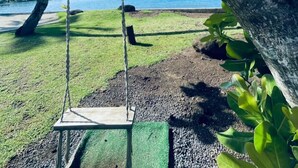 A swing set under a tree with a sign indicating a view of the water. - Sublime Tahiti Beach Retreat (Teva I Uta)
