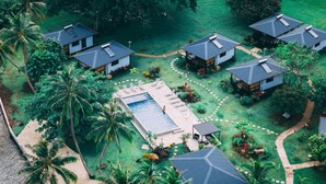 A resort with multiple bungalow-style buildings, a central swimming pool, and lush tropical landscaping. - Sublime Tahiti Beach Retreat (Teva I Uta)
