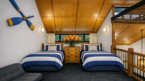 Una camera da letto con due letti, soffitto in legno, comodino, cassettiera, divano grigio e una finestra con tende.