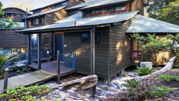 Una casa moderna con facciata in legno, un portico coperto e un piccolo terrazzo.