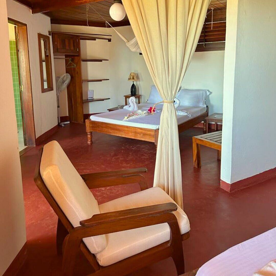 Un dormitorio con cama, una silla, una mesita de noche y una lámpara colgante.