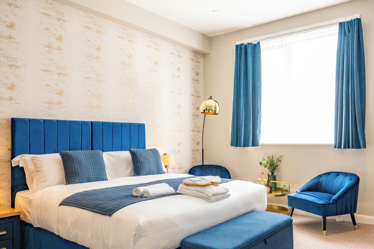 A modern bedroom with a large bed, a desk, and a chair.