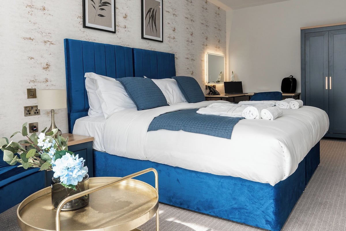 A modern bedroom with a large bed, a bedside table, a lamp, and a decorative vase.