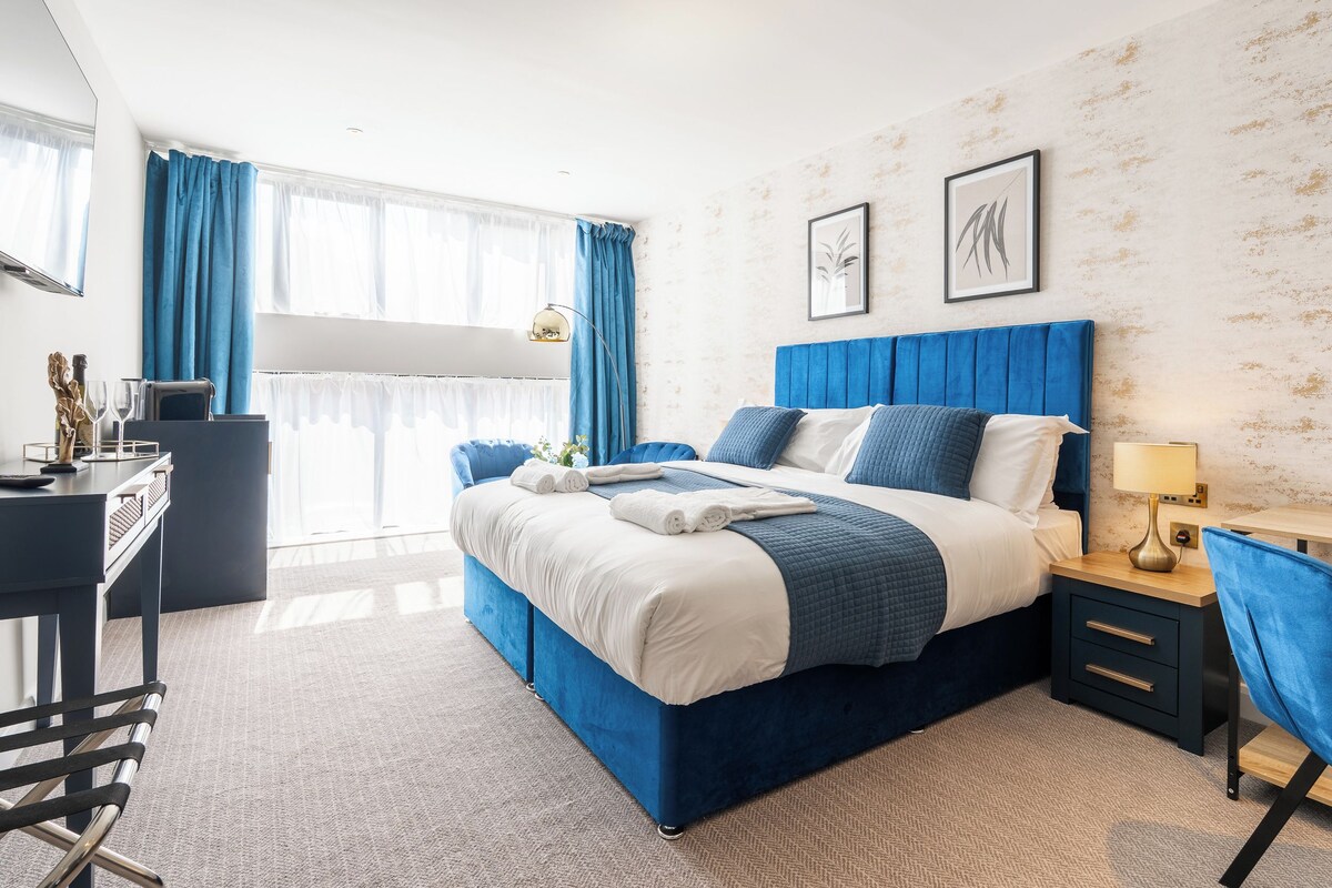 A modern hotel room with a large bed, a desk, and a chair.