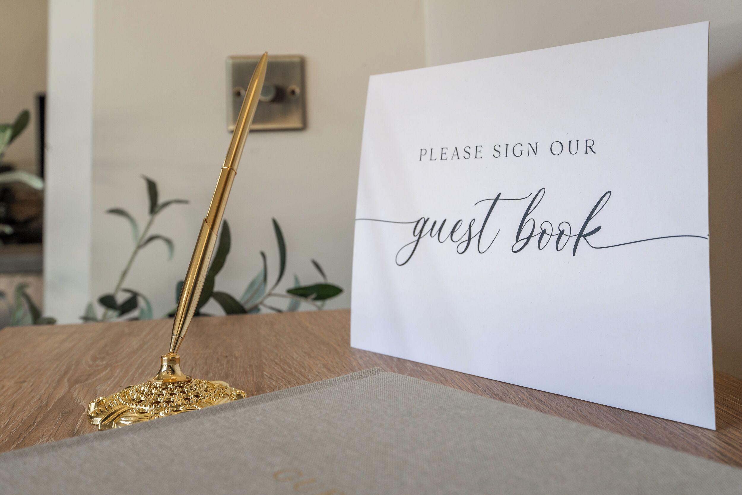 Une pancarte sur fond blanc avec l’inscription : « Veuillez inscrire votre nom dans notre livre d’or ».