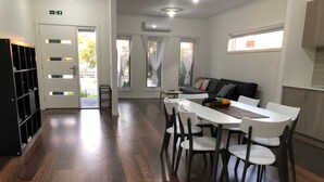 Una cocina moderna con zona de comedor, suelo de madera y estantería empotrada.