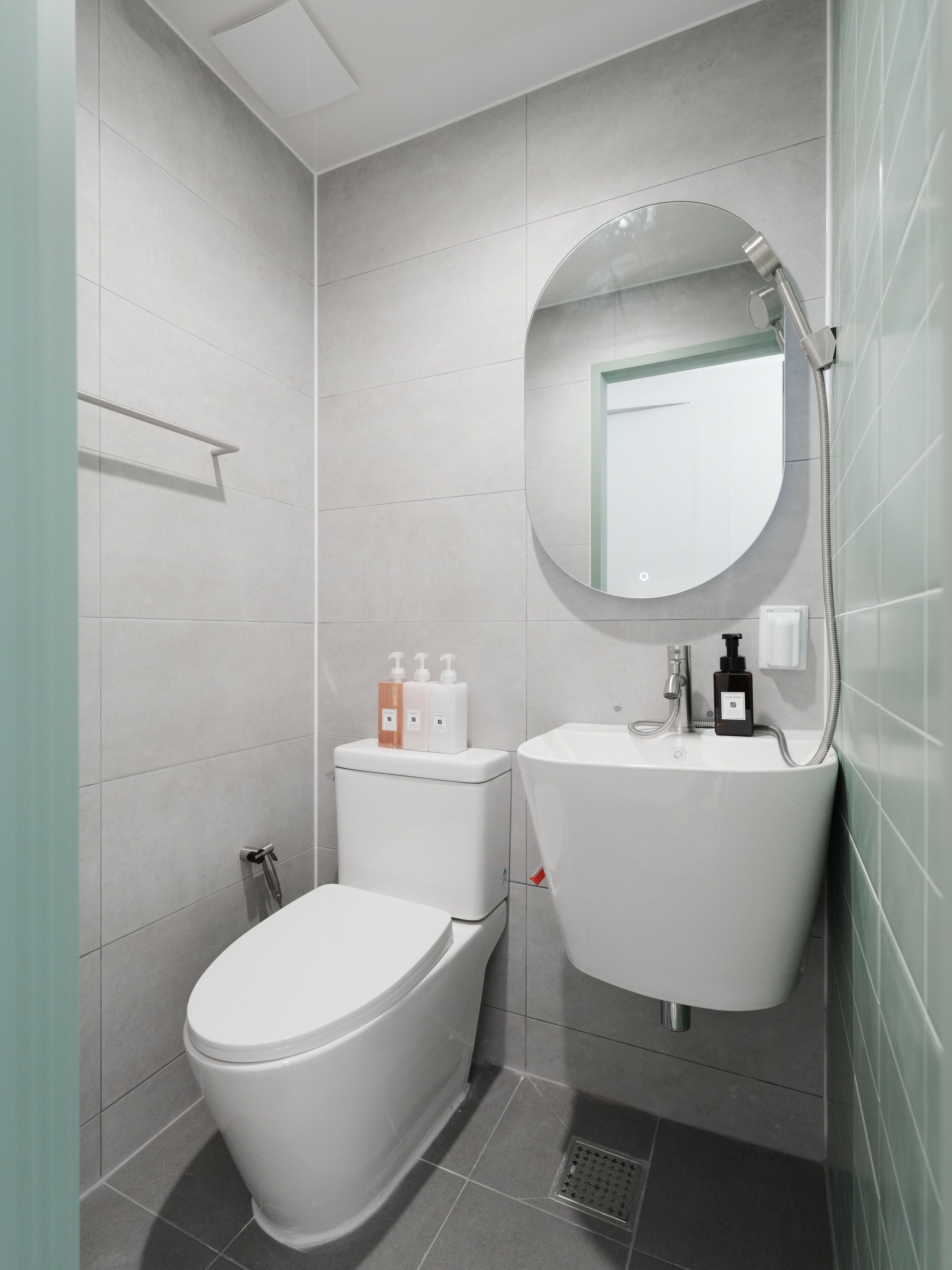 A modern bathroom with a toilet, sink, and mirror.