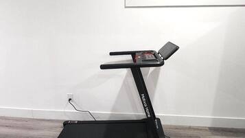 Una cinta de correr en una habitación con pared blanca y ventana.