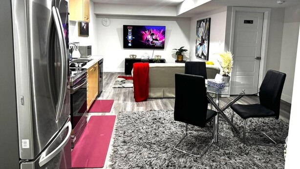 A compact living space with a kitchen, dining area, and a TV mounted on the wall. - Gateway to Serenity-welcome Home (London)