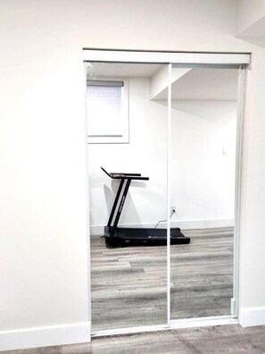 A room with a sliding glass door leading to a space containing a treadmill.