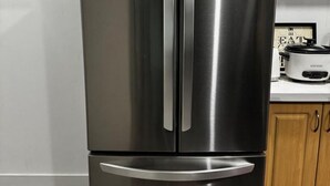 A stainless steel LG refrigerator in a kitchen with wooden cabinets and a countertop. - Gateway to Serenity-welcome Home (London)