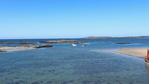 Vista costera con aguas azules cristalinas, playa arenosa y barcos.