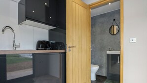 Una cocina moderna con gabinetes negros, una puerta de madera y un inodoro visible en el baño contiguo.