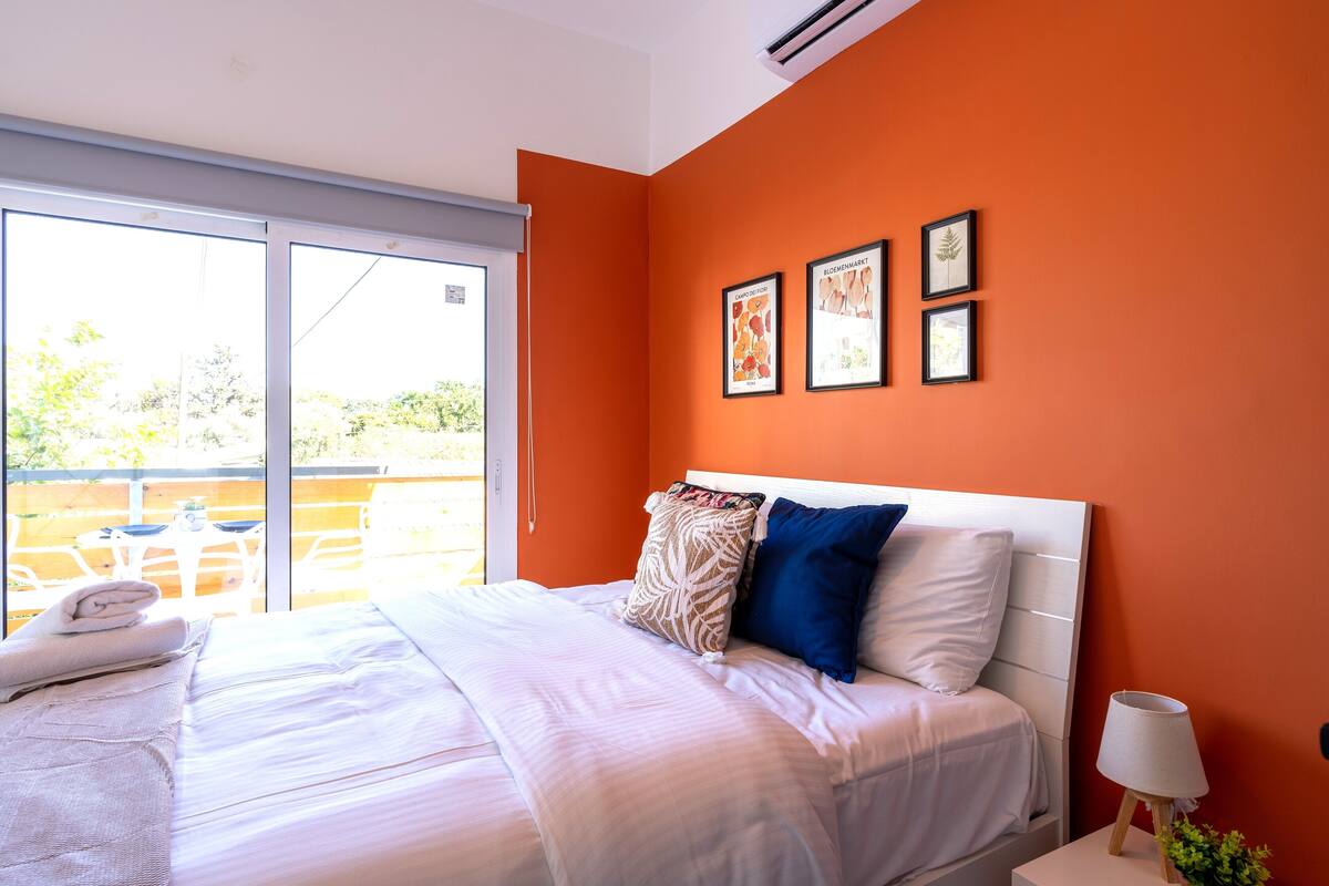 Un dormitorio con una cama grande, una mesita de noche con lámpara y una ventana con vistas al exterior.