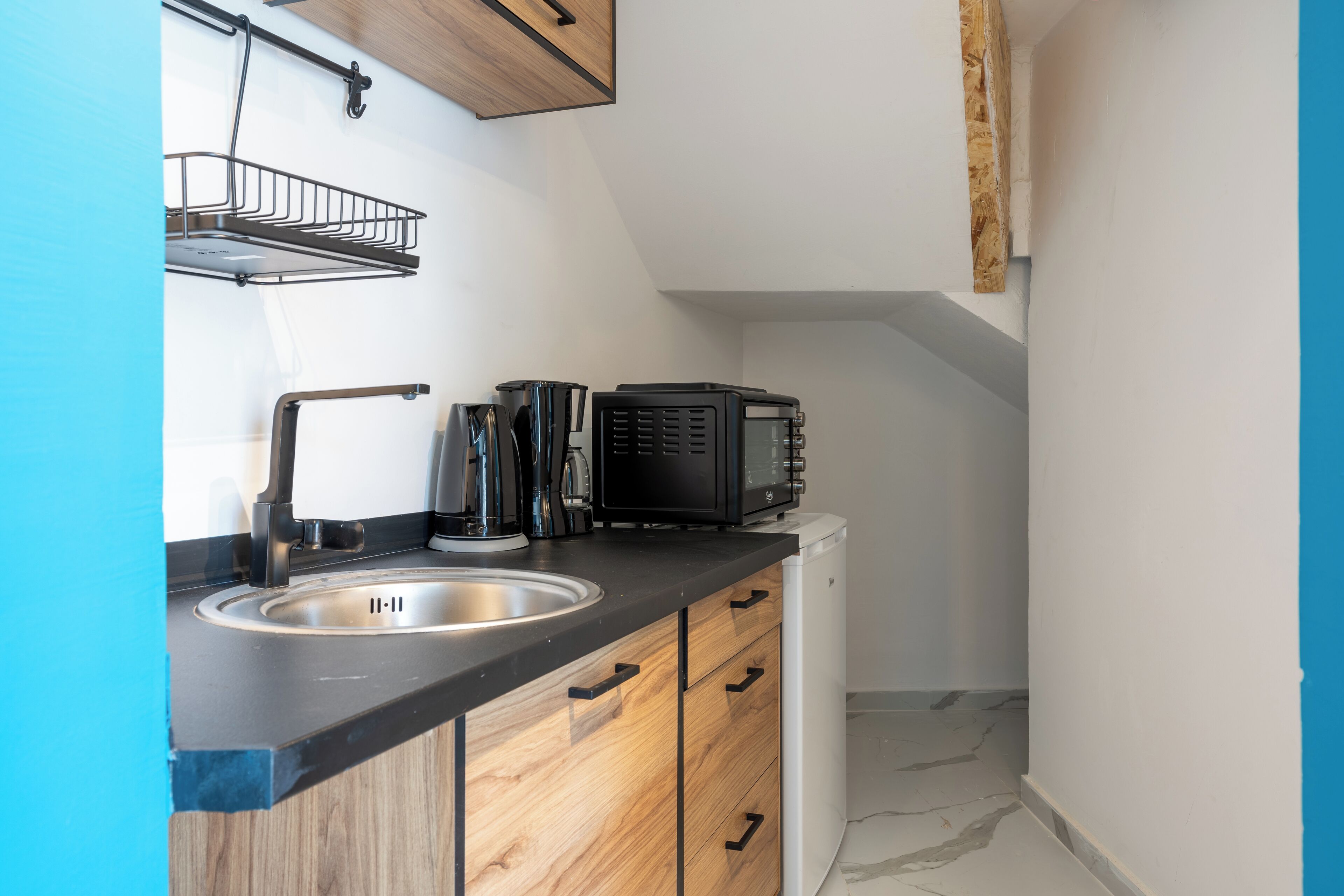 A compact kitchen with a sink, wooden cabinets, and a black countertop.