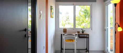 A modern room with a large window, a desk, a chair, and a lamp.
