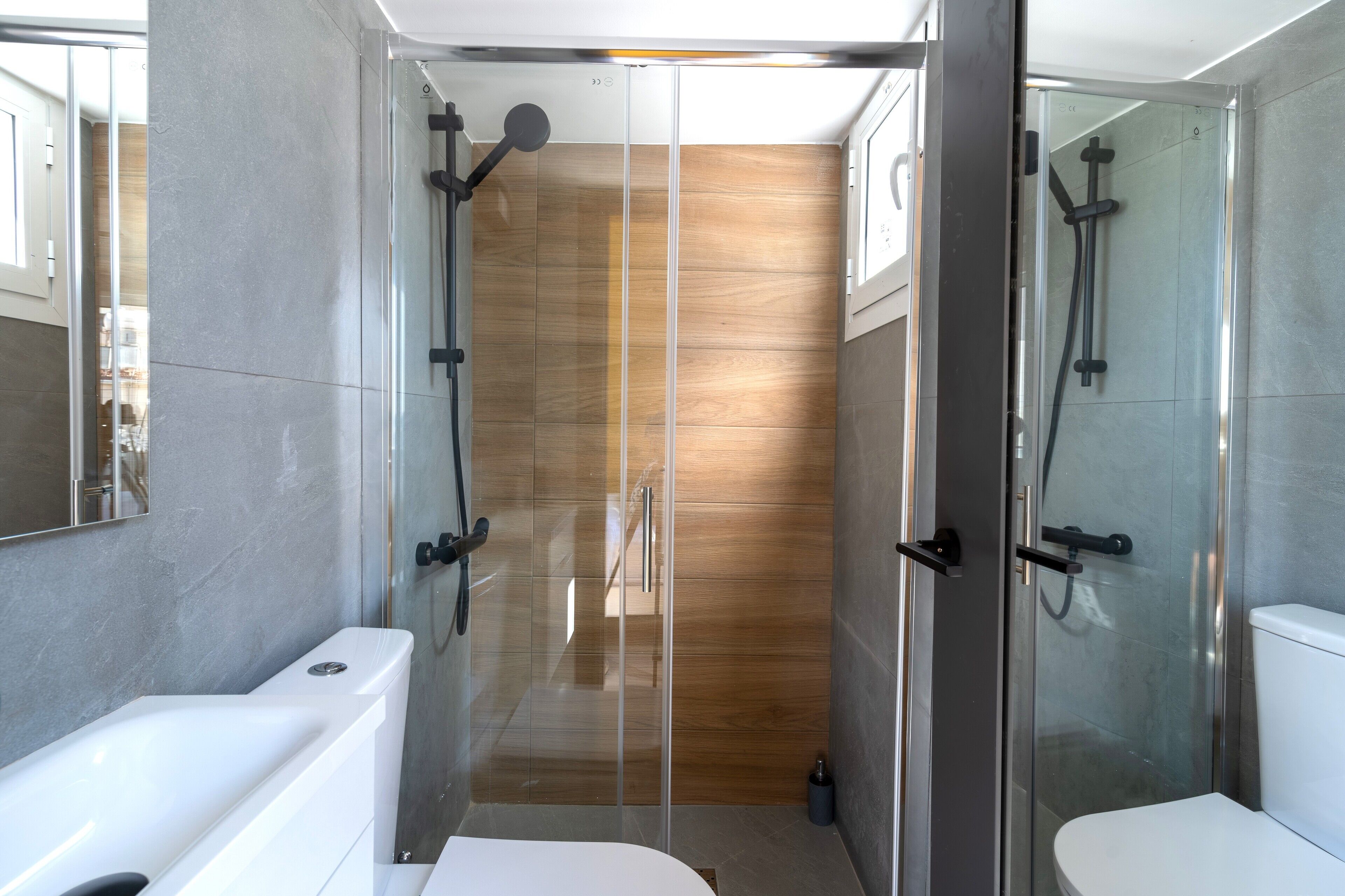 Un baño moderno con ducha envuelta en vidrio, inodoro blanco y bañera.