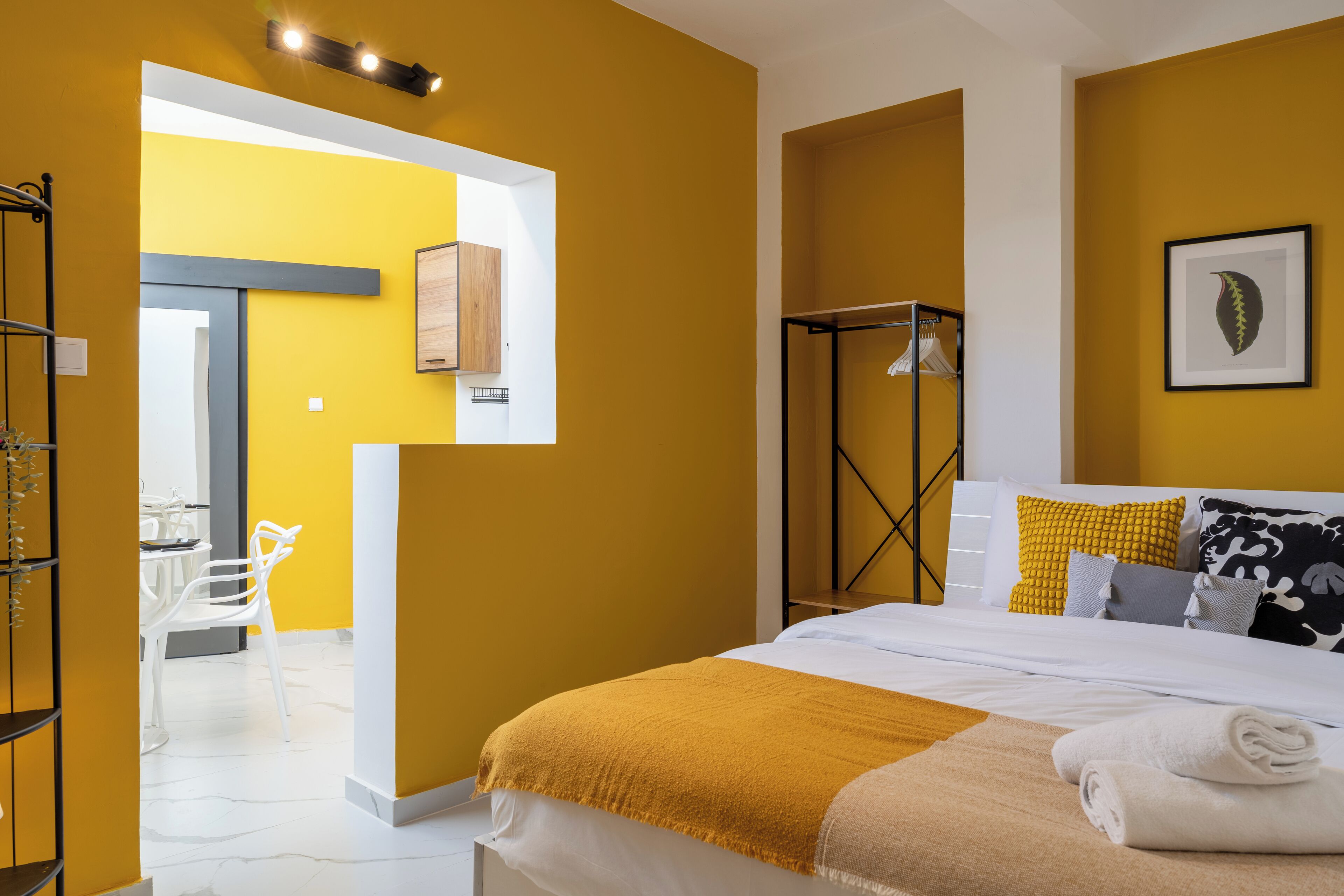 A hotel room with a bed, a bedside table, a wardrobe, and a bathroom visible through an open door.