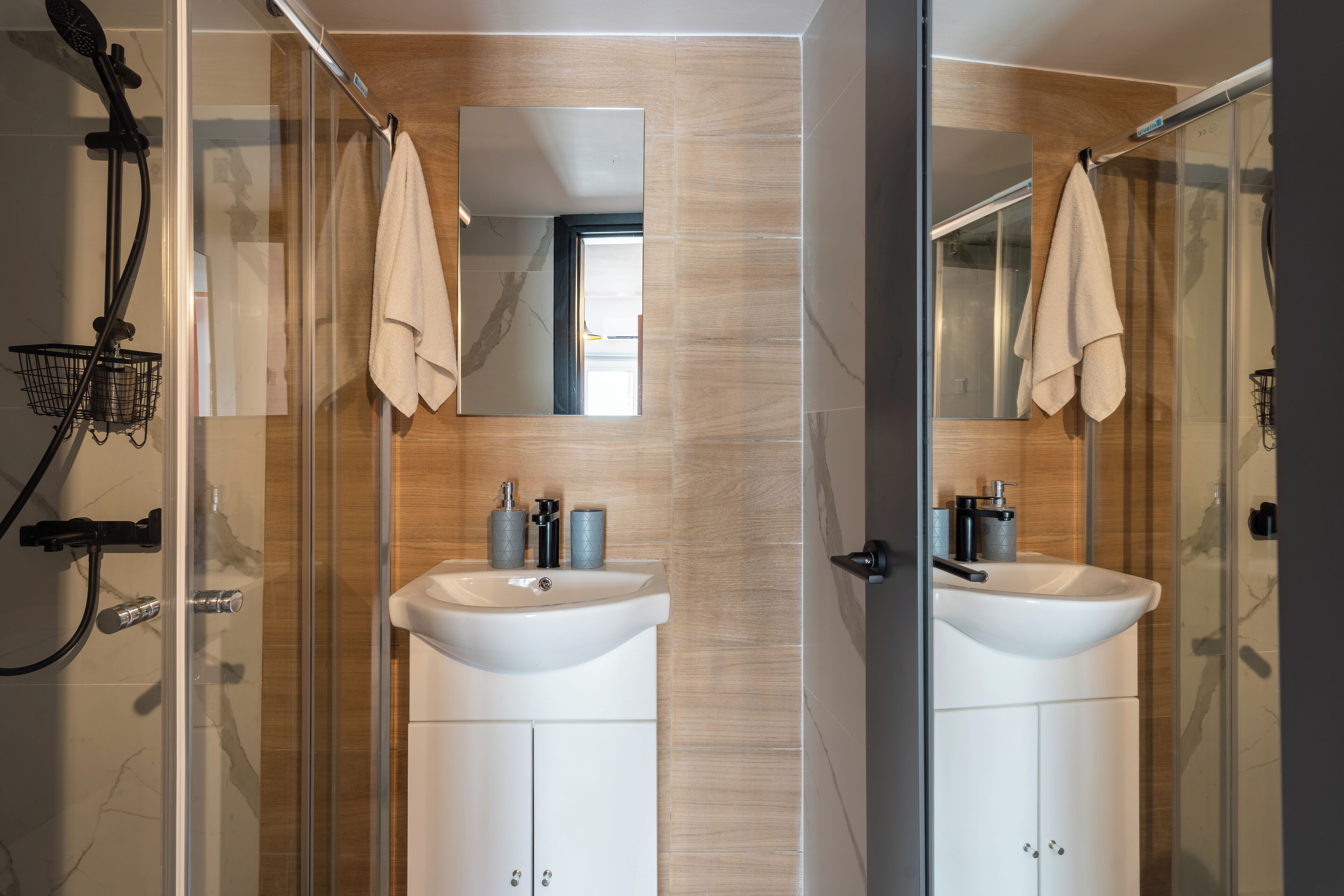 Un baño moderno con dos lavamanos, ducha y cabina de ducha de vidrio.