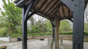A stone-paved courtyard with a wooden gazebo structure, surrounded by greenery and stone walls. - Donagh Cross Town House (Carndonagh)