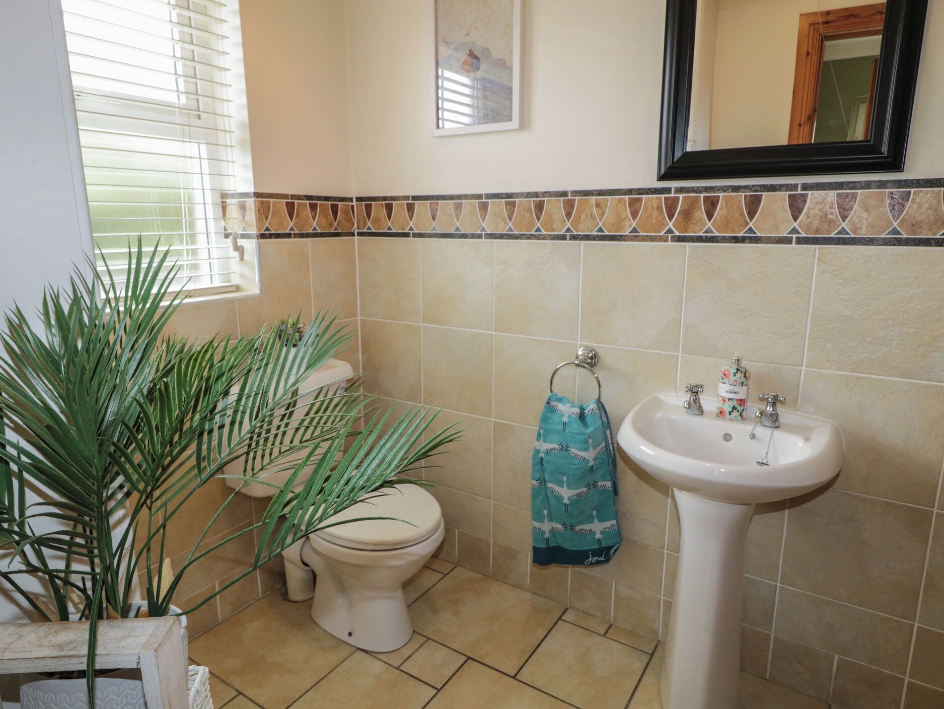 Ein Badezimmer mit Toilette, Waschbecken und dekorativer Fliesenzierleiste.