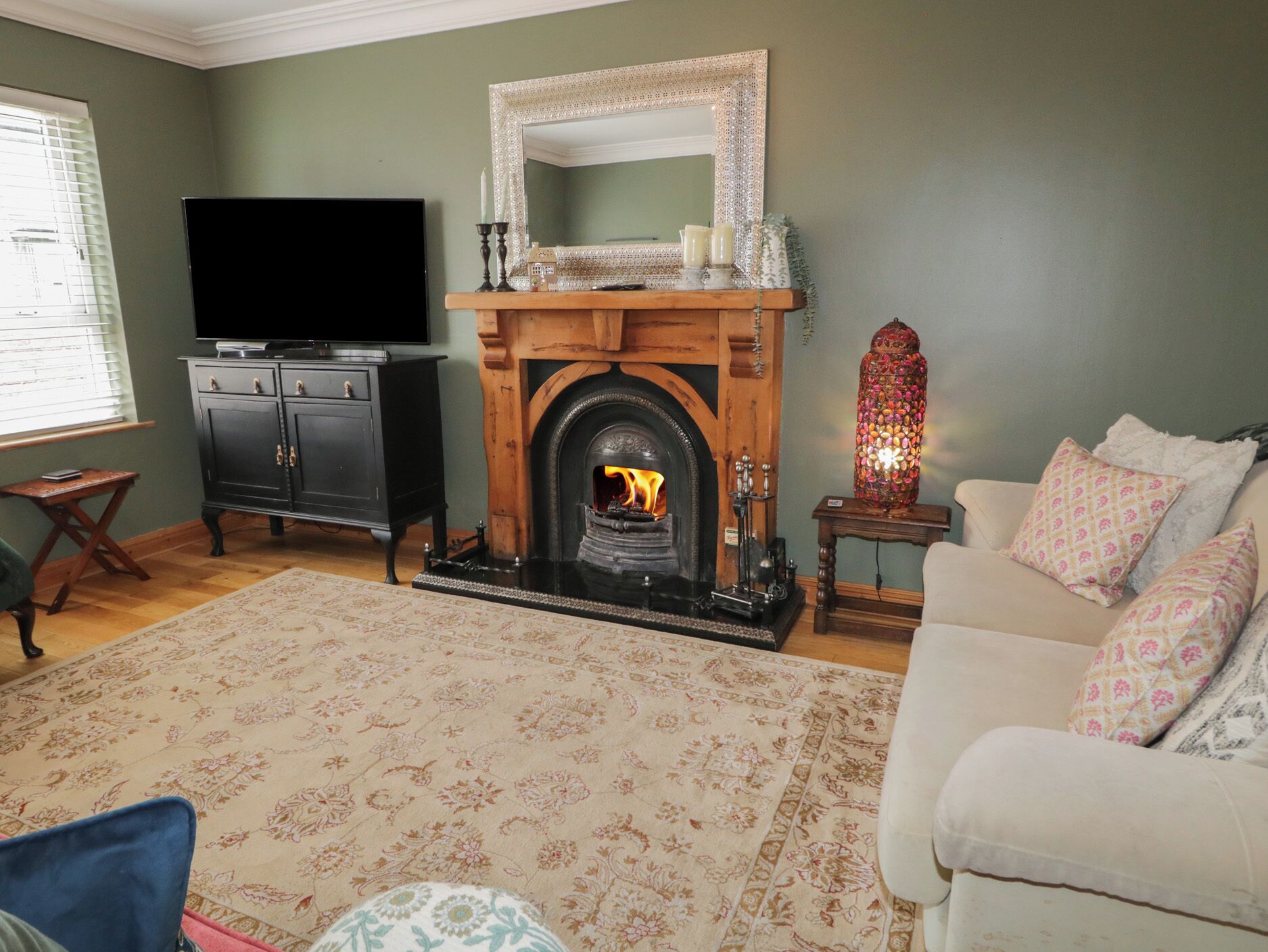 A living room with a fireplace, a television, a sofa, and a patterned rug.