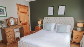 A bedroom with a large bed, wooden dresser, and a mirror. - Donagh Cross Town House (Carndonagh)