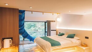 Una habitación de hotel moderna con cama, mesita de noche y vistas al exterior.