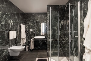 Un baño moderno con ducha de vidrio, lavamanos independiente y tocador con espejo.