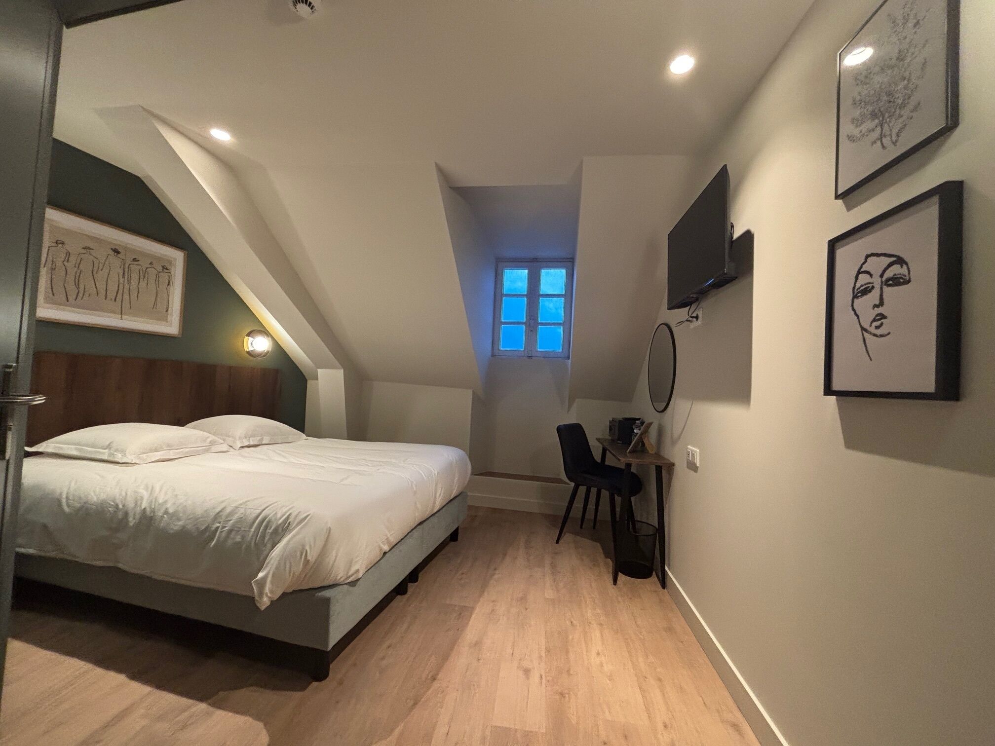 Una camera da letto con un letto, una scrivania, una sedia, una finestra e opere d'arte alle pareti.