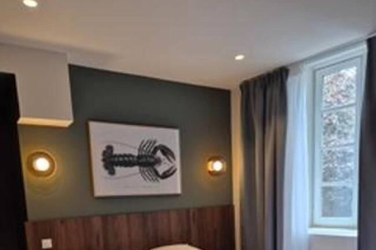 A neatly made bed in a room with a wooden floor, a headboard, and a wall-mounted artwork.