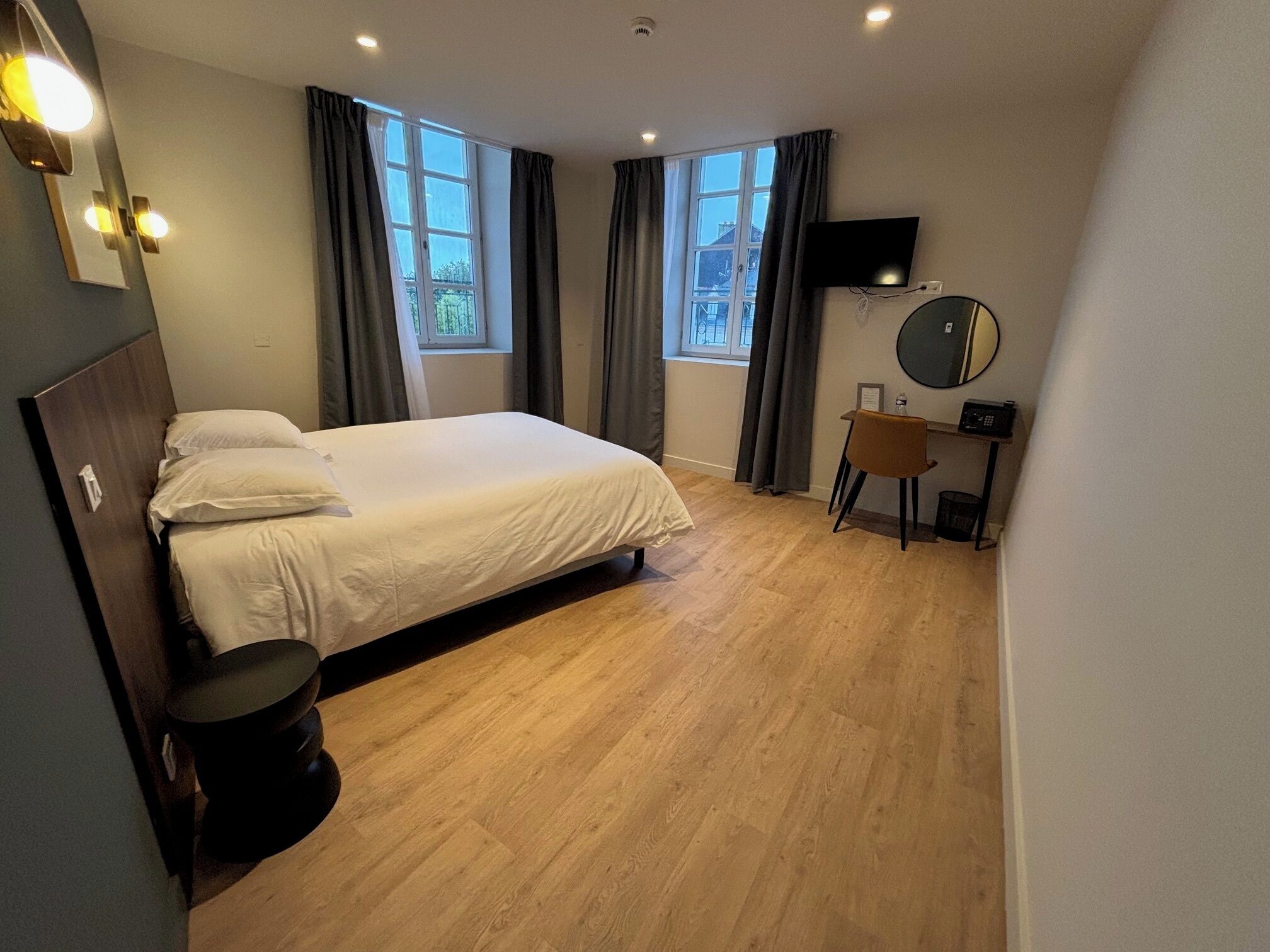 Un dormitorio con una cama, un escritorio con una silla, un televisor y una ventana.