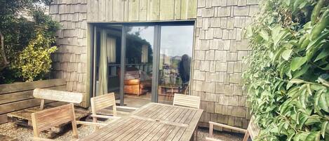 A wooden building with a circular skylight, large glass doors, and a patio with wooden furniture.