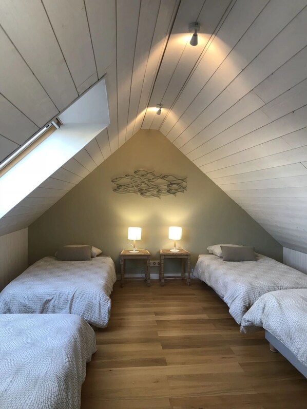 A cozy attic bedroom with two beds, wooden floors, and a sloped ceiling with a decorative fish mural. - EMBRUNS D'HERBE SLOW CAMP (Plogoff)