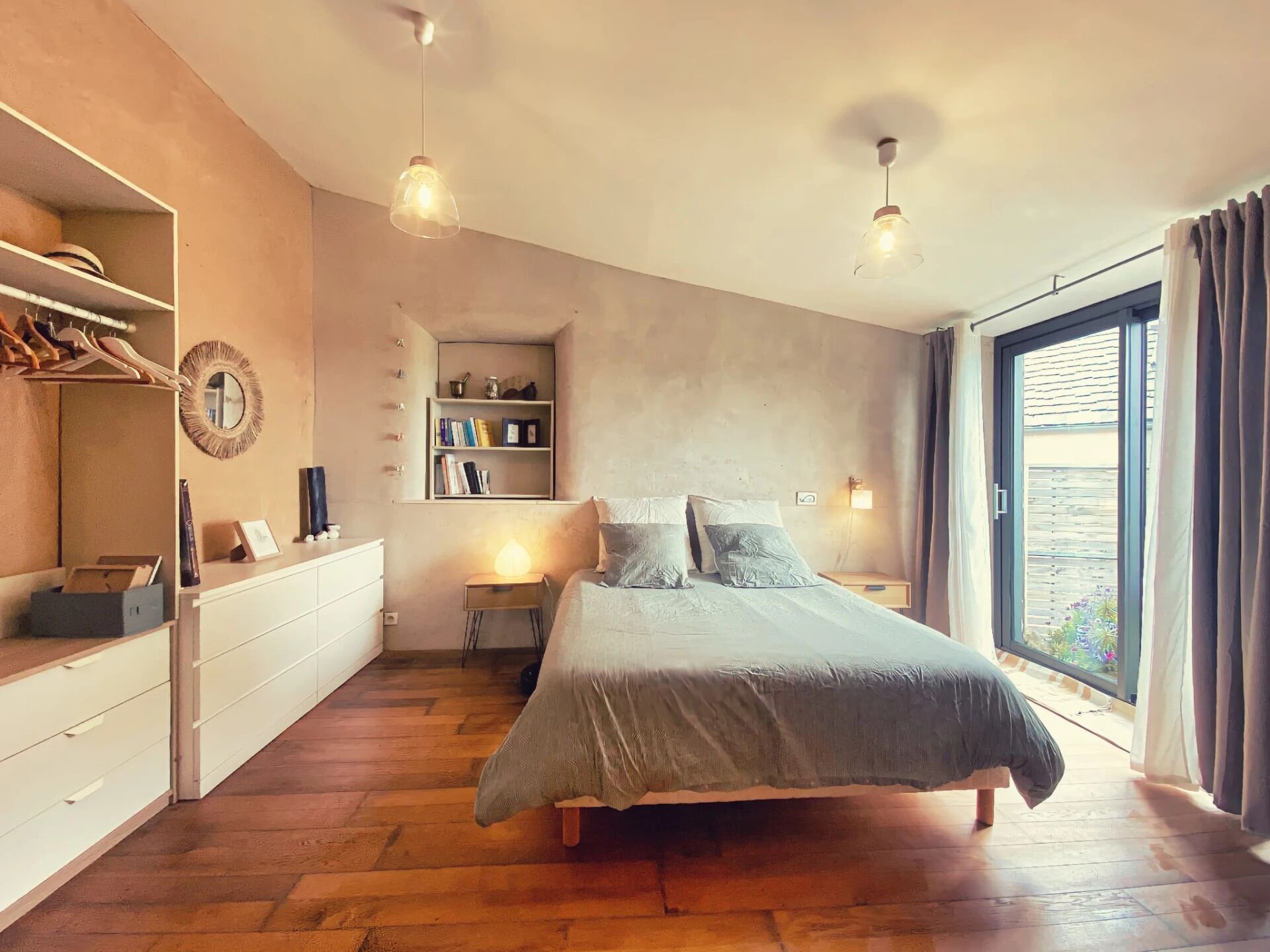 A bedroom with a bed, bedside tables, a wardrobe, a bookshelf, and a large window with curtains.